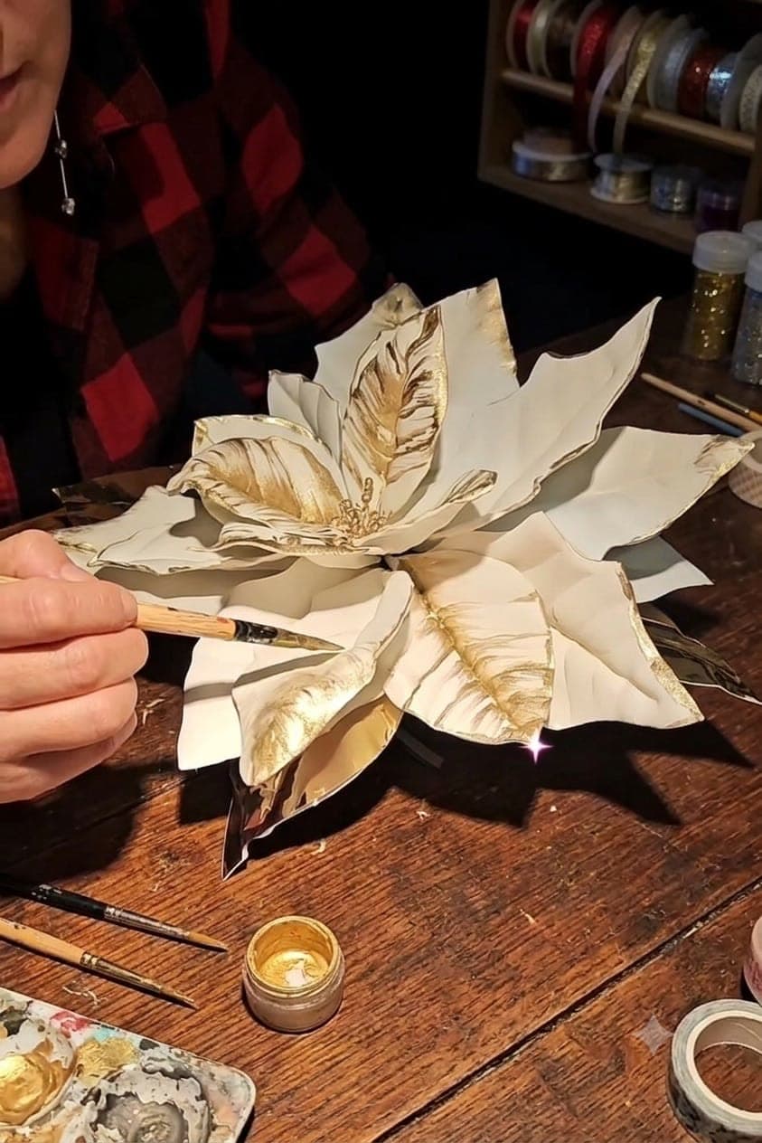 Le mani di Francesca dipingono d'oro i petali di una stella di Natale