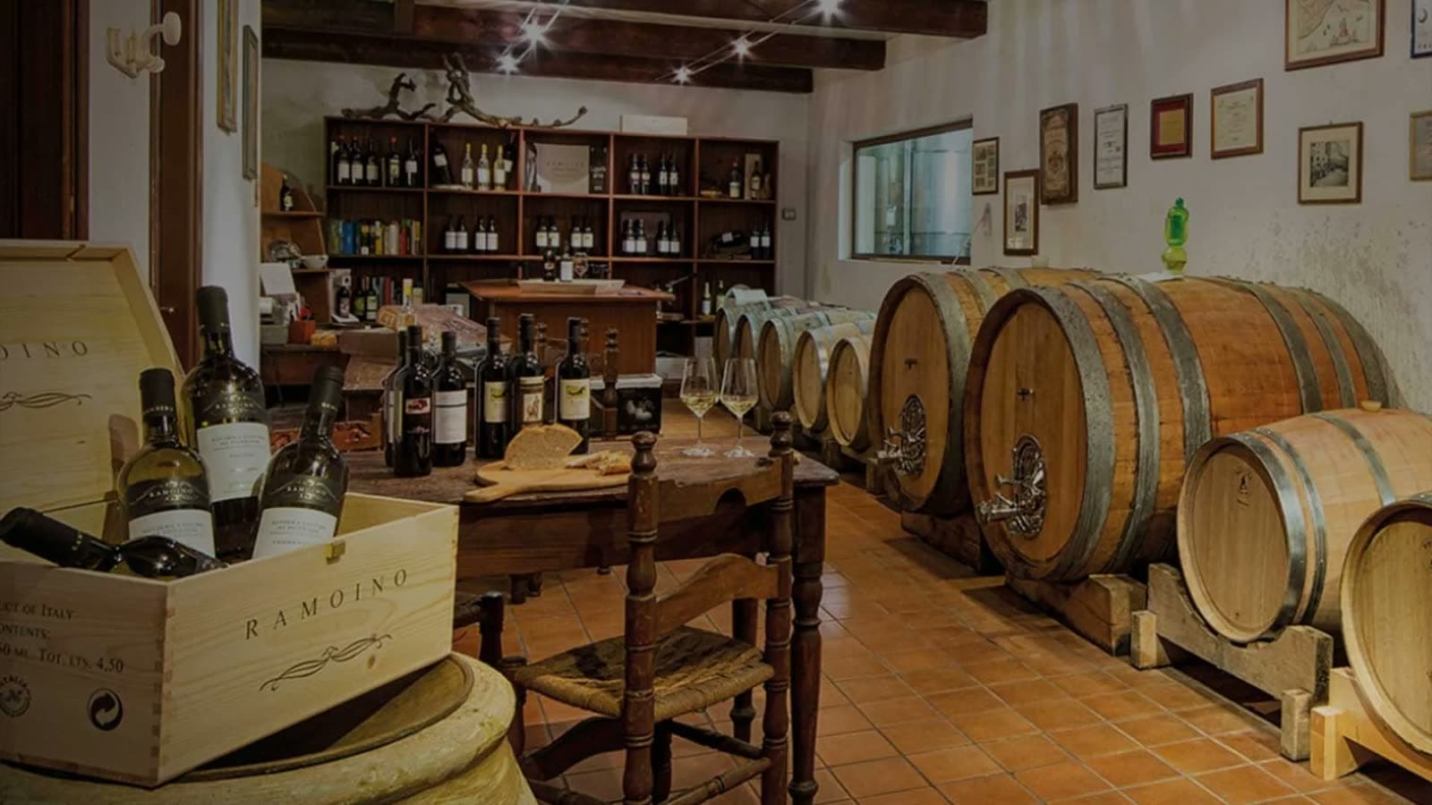 La cantina Ramoino a Sarola, con le botti di rovere e una cassetta di bottiglie
