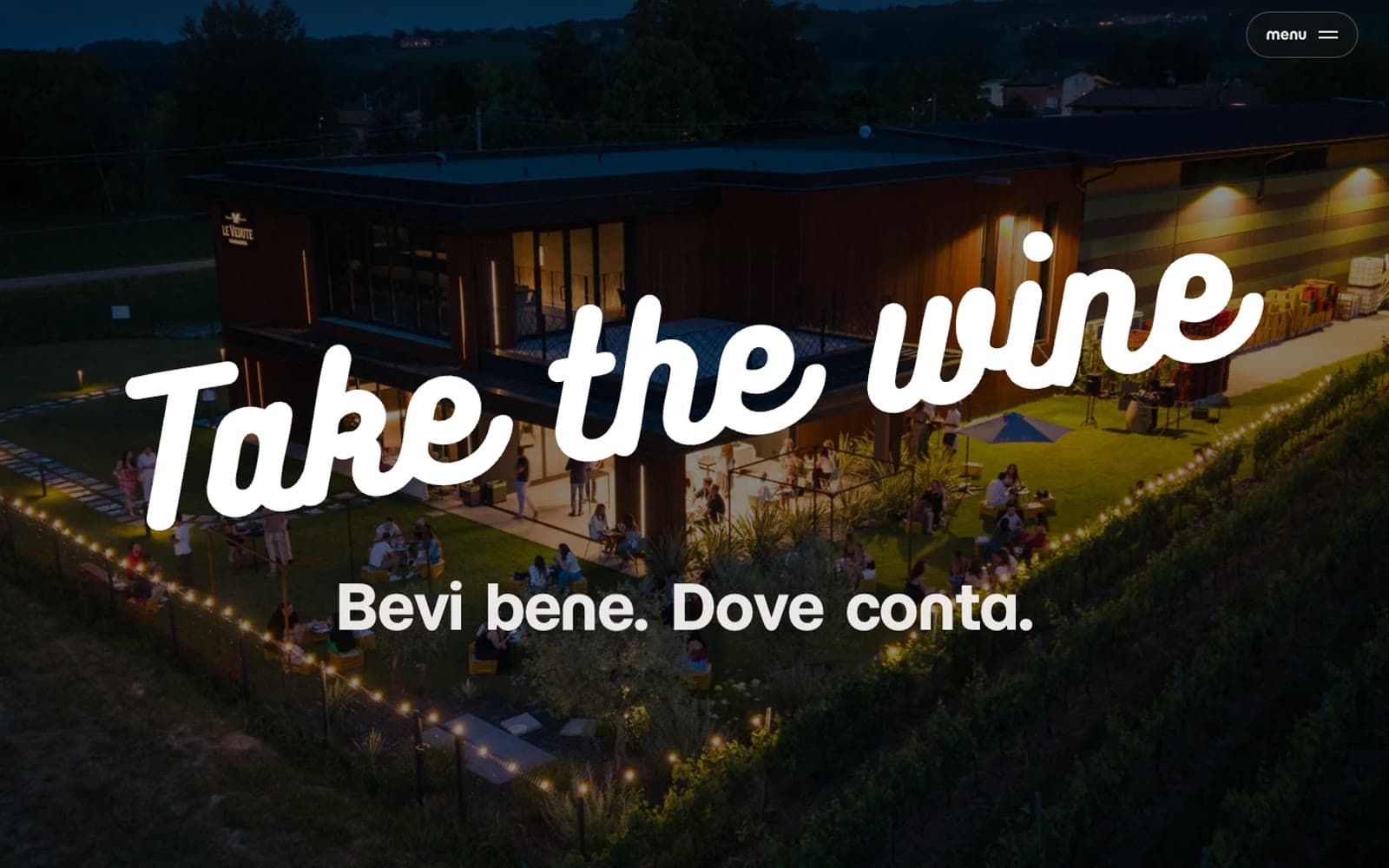 La home del sito: il logo Take the wine sopra una cantina illuminata di sera